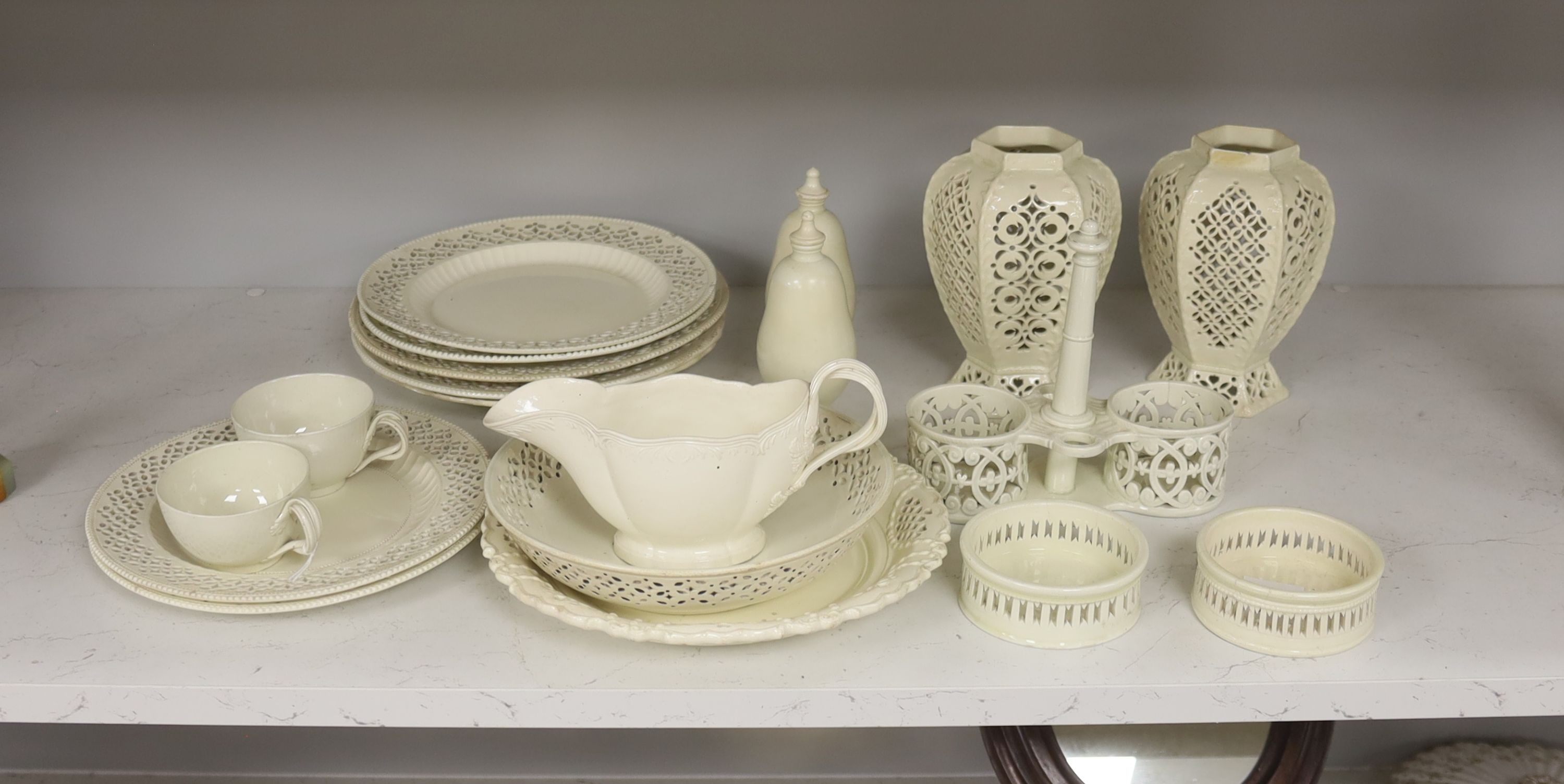 A collection of creamware, circa 1800, Staffordshire and Yorkshire comprising three pairs of plates, with moulded laurel swags, pair of small bottle coasters, sauceboat, saucer dish, two teacups, cruet stand, two pear sh